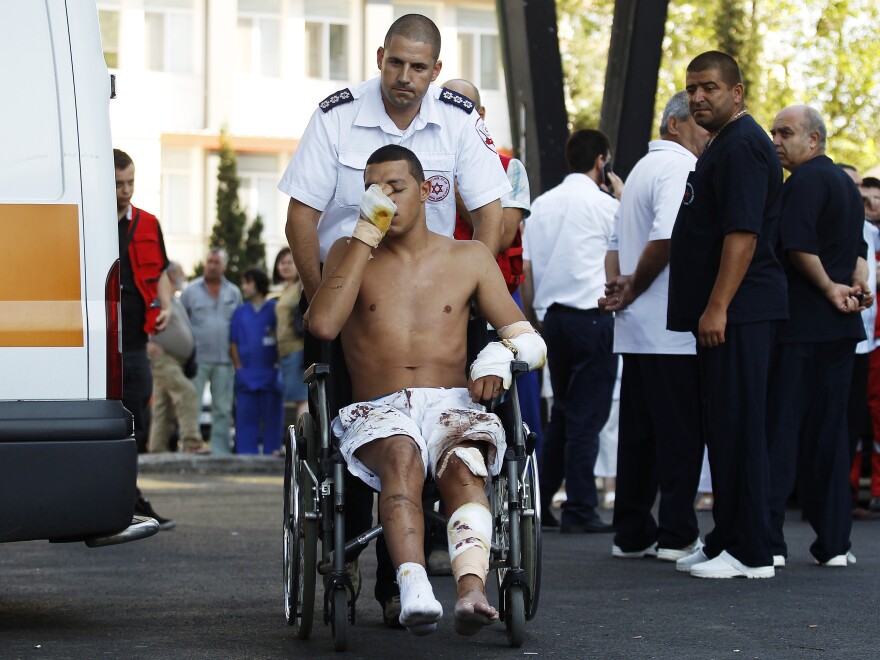 An Israeli survivor is carried on a wheelchair to an ambulance as he leaves a hospital in Burgas, Bulgaria, on Thursday. A suicide bomb attacker killed eight people in a bus transporting Israeli tourists at a Bulgarian airport, the country's interior minister said, and Israel pointed its finger at Iranian-backed Hezbollah militants.