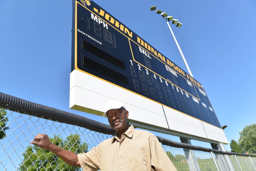 Glasgow resident Don White stands in front of the scoreboard at the high school baseball field dedicated in honor of Negro Leaguer John Donaldson.