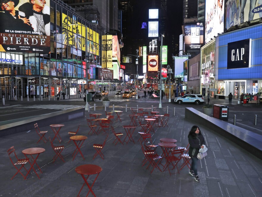 A woman walks through a nearly deserted Times Square in New York Monday, as the city adjusts to widespread closures and restrictions on public life because of the COVID-19 respiratory disease.