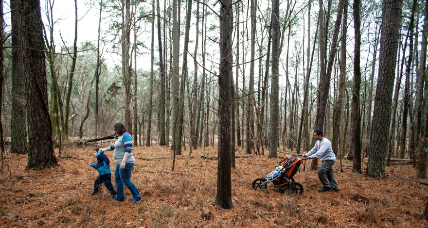 Roan Fields-Moffitt, left, walks with his mother, Desiree Moffitt, second from left, and father, Jacob Fields, right, as he pushes the family's baby twin daughters through a wooded area adjacent to Murdoch Developmental Center in Butner