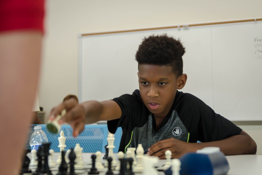 Jason Stokes, 10, reaches to make a move Friday, July 13, 2018, during a St. Louis Chess Club summer camp at Saint Louis University.