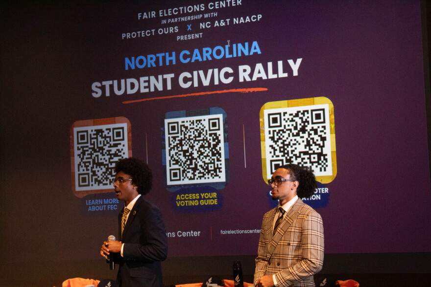 Two students speaking in front of a screen.
