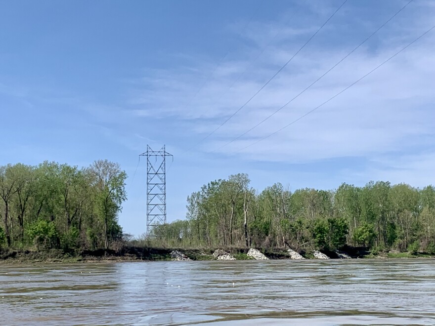 A large scale transmission line cuts the treeline on the shore of the Missouri River. 