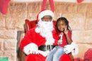 little sits on Santa's lap showing a peace sign