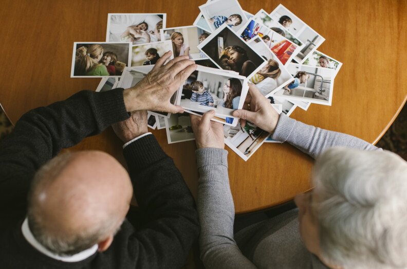 Two people sit looking at pictures at a table.