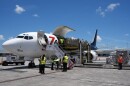 People load pallets containing food and hygiene kits into a cargo plane