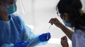 A woman is instructed on how to swab her nose by a medical worker at a free COVID-19 testing site in July 2020 in Chelsea. (David Goldman/AP)