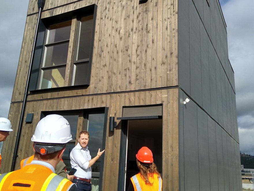 A man gestures at a structure made from cross-laminated timber.