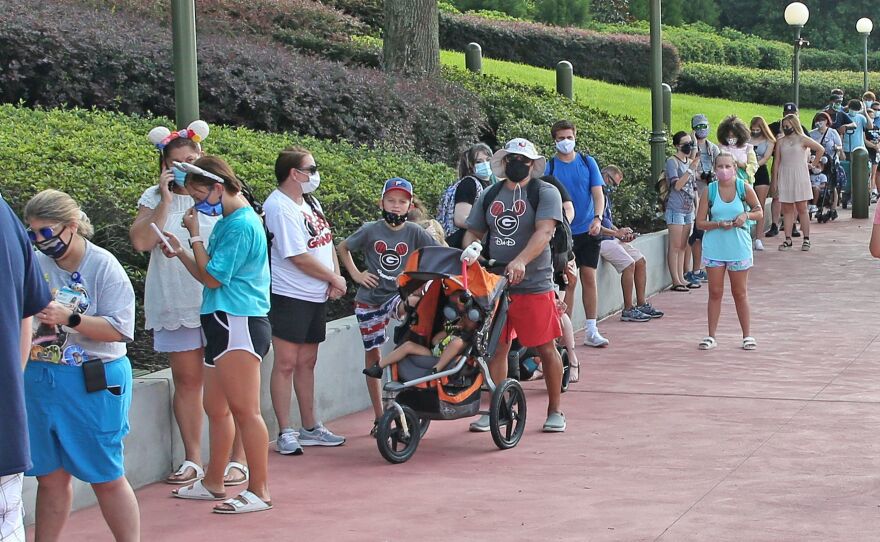 Guests wearing protective masks wait to pick up their tickets at the Magic Kingdom park. Reservations are required as well as masks and temperature checks prior to entering the park.