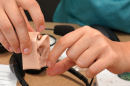 A health care professional demonstrates a hearing aid at a previous M