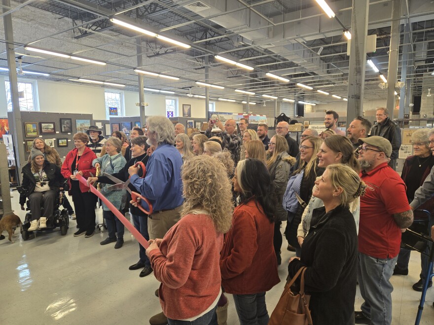 Society President Paul Johns (center, in blue) prepares to cut the ribbon on the museum's reopening.