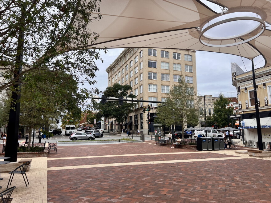 A brick- paved pedestrian square in downtown Athens with beige shade sails hovering above.