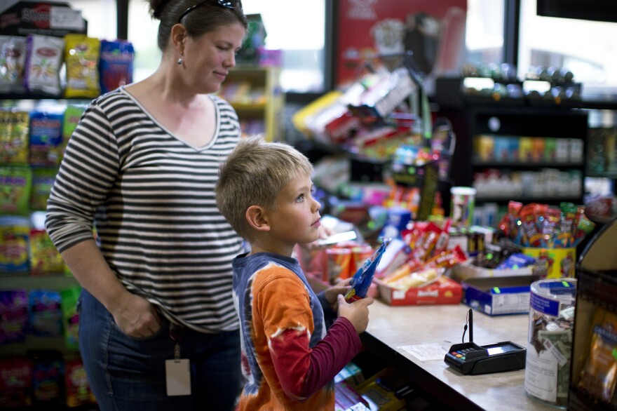 Matthew makes a transaction at the counter of a local market in his neighborhood.