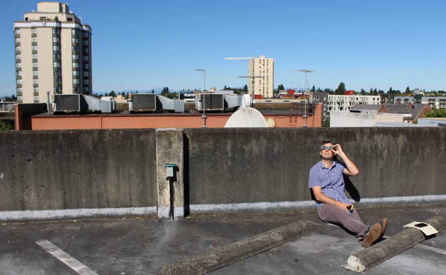 Record producer/editor Jason Pagano watches the eclipse from the roof of the KUOW garage.