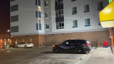 Black police SUV parked in a parking lot in front of a store and next to a large apartment building