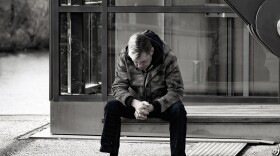 A person sits alone on a bench.