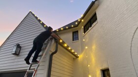 Levi Carlson clips Christmas lights to the gutter of a south Charlotte home. Carlson works part-time for Christmas Lights and More Much, a Charlotte-based holiday decorating company.