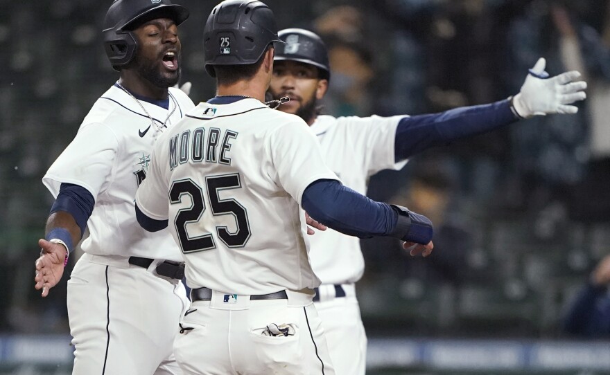 Seattle Mariners' Taylor Trammell, left, greets Dylan Moore (25) at the plate after they scored during the eighth inning of the team's baseball game against the San Francisco Giants, Thursday, April 1, 2021, in Seattle. 