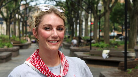 a blonde woman in a park smiles at the camera 