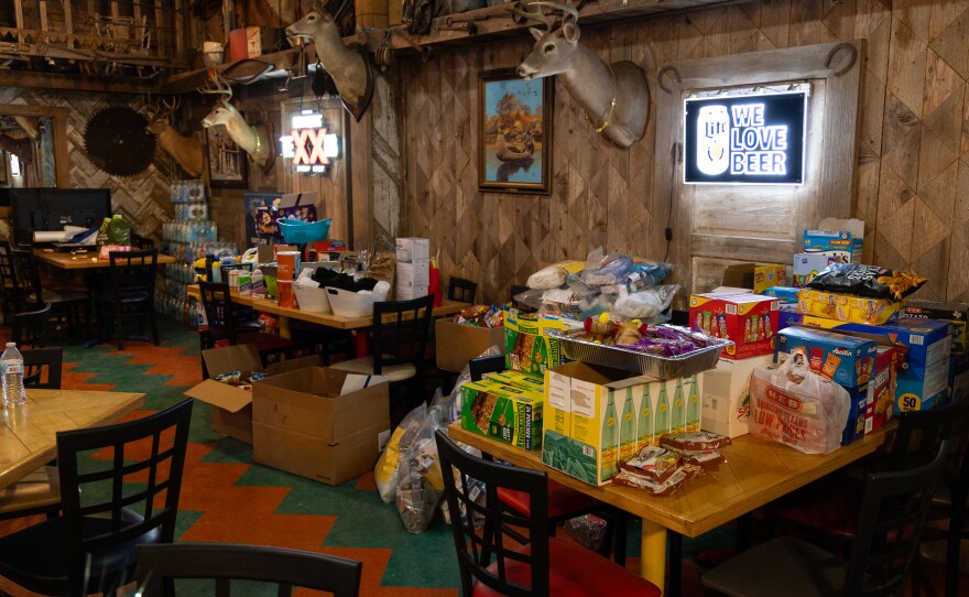 Packages of water, snacks and other donations lined the back wall inside Howdy's.