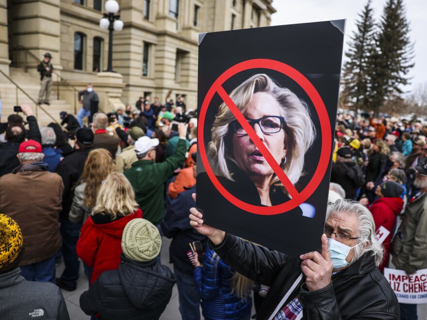A man holds up a sign against Rep. Liz Cheney, R-Wy., as Rep. Matt Gaetz, R-Fla., speaks to a crowd during a rally against her on Thursday in Cheyenne, Wyoming.