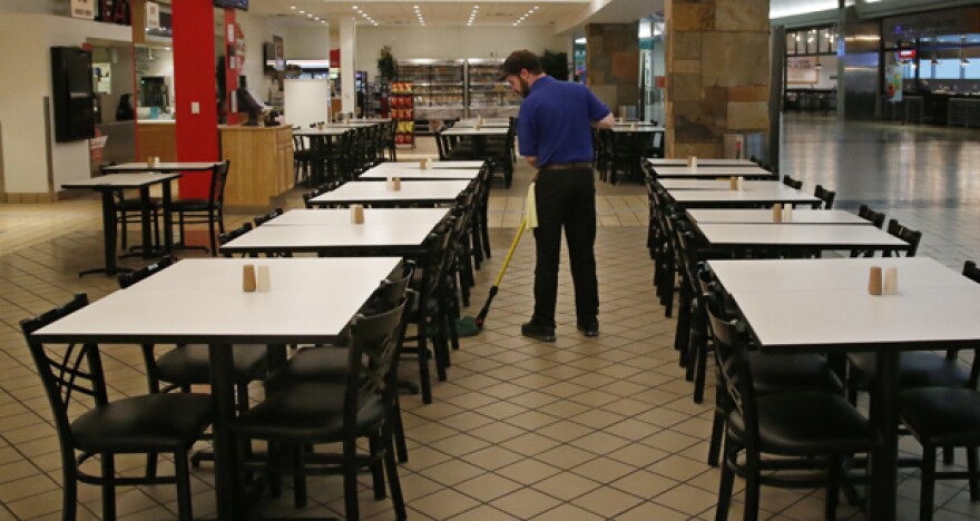 A worker mops the floor at a nearly empty food court at Will Rogers World Airport in Oklahoma City, as airlines limit flights due to the virus outbreak. 