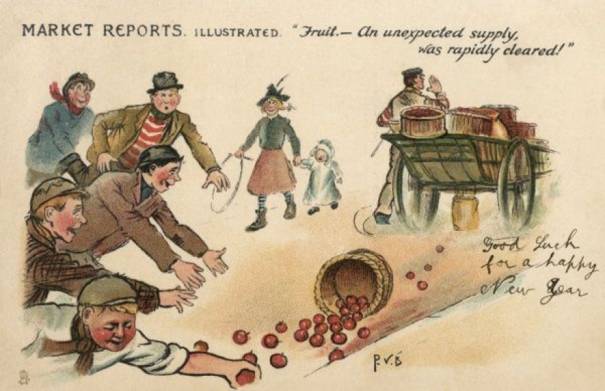 A person with a wagon filled with baskets of red apples, one brown basket of apples fell off the wagon and there are 5 people jumping on the ground to attempt and pick up the fallen apples