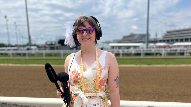 A reporter holds recording equipment trackside at Churchill Downs.