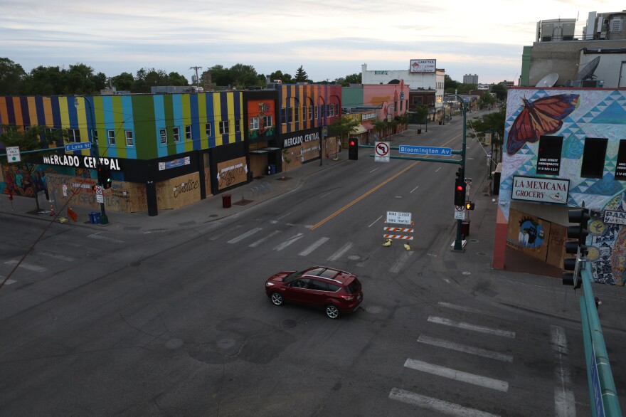 A car drives by boarded-up businesses as it crosses Lake Street in Minneapolis. Volunteers, sometimes armed, are working together to protect homes and businesses.