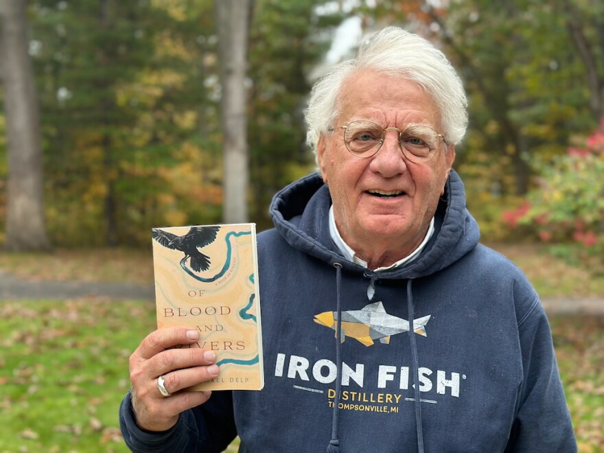Author Michael Delp poses with a copy of his new book, "Of Blood and Rivers," a collection of elegies about grief and loss. (Photo: Ed Ronco/IPR News)