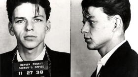 Frank Sinatra poses for a mug shot after being arrested and charged with "carrying on with a married woman".
