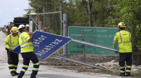 Workers install a sign reading "Alligator Alcatraz" at the entrance to a new migrant detention facility at Dade-Collier Training and Transition facility, Thursday, July 3, 2025, in Ochopee, Fla. (AP Photo/Rebecca Blackwell)