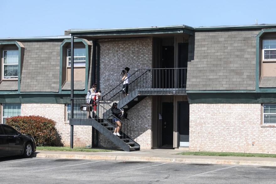 Three people walk down stairs at the Mount Carmel apartment complex in East Austin.