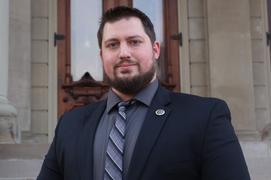  An image of Michael VandeGuchte wearing a suit and a pin with the city of Lansing logo.