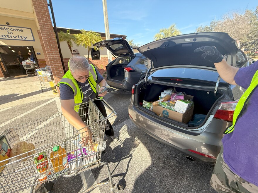 a man putting food into the trunk of a small sedan