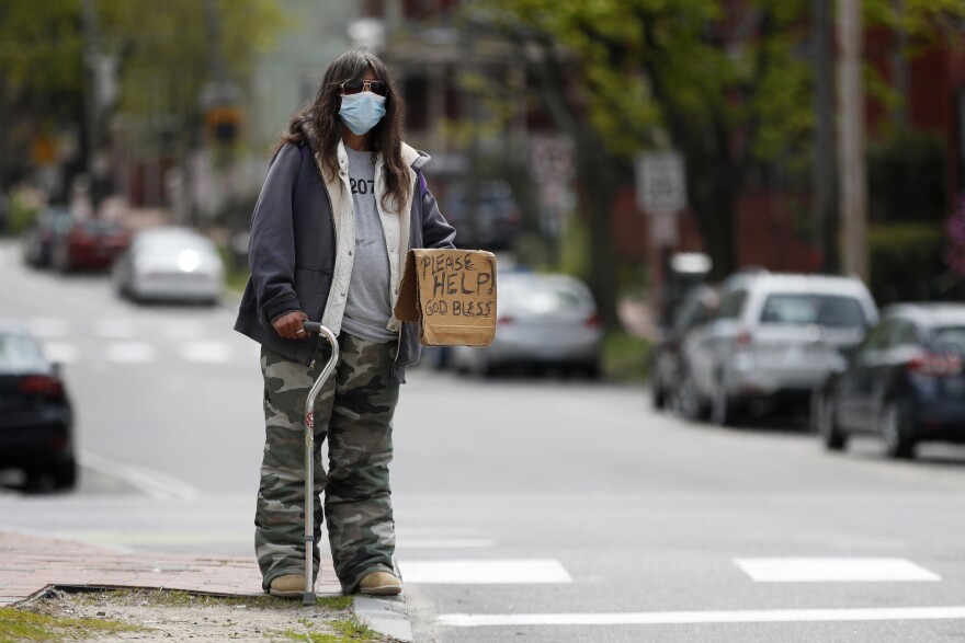 Terry Rann, a homeless woman, wears a mask while panhandling during the coronavirus pandemic Friday, May 15, 2020, in Portland, Maine. State officials reported another 38 diagnosed cases of the coronavirus on Friday.