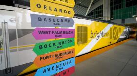  A sign post is seen in front of a Brightline rail car to celebrate the completion of the construction of the Brightline high speed rail on Wednesday, June 21, 2023, in Orlando, Fla. The rail system now connects Miami to Orlando. 
