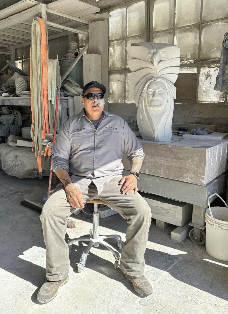 Jason Quigno posing with a sculpture at Asinaabe Studios in Grand Rapids