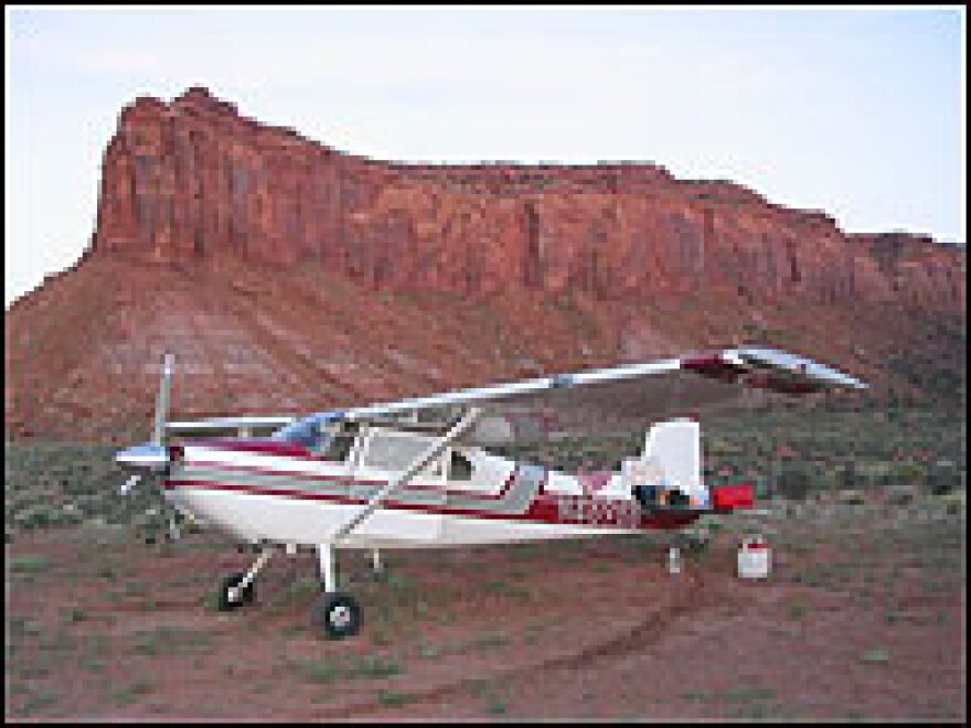 Collier's Cessna parked by a butte.  Collier and his plane are both in their 50s.