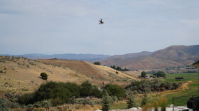 A helicopter pulls water from a pond near Bret Hadley's home to fight the Rocky Canyon Fire, Aug. 12, 2026.