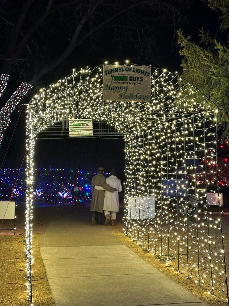 A couple walks under a lit archway at Washington Park