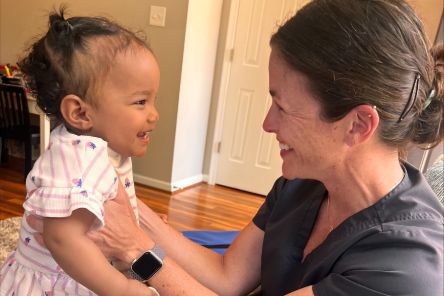 Molly Curtis, registered nurses at Navy-Marine Corps Relief Society’s Visiting Nurse Program, interacts with a child during a home visit with a military family.