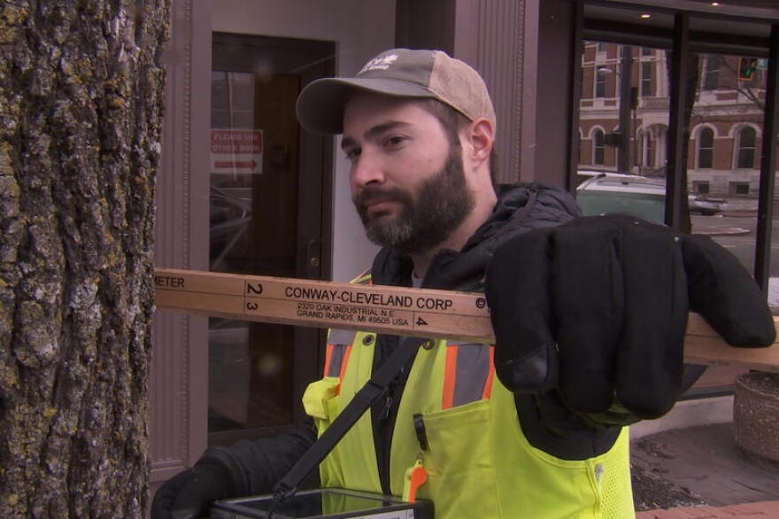 Tyler VanVlerah of Davey Resource Group measures the size of a tree in downtown Columbus. Once the inventory is done, the city will be able to use an interactive map where it can find details about this specific tree.