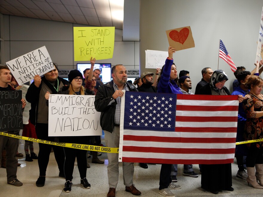 Demonstrators at Dallas-Fort Worth International Airport gather on Saturday to protest President Trump's executive order temporarily barred refugees and citizens of seven countries.