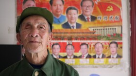 Yu Zu'en stands in front of one of the few wall decorations in his new, government-issued apartment: a poster of China's leaders. The 84-year-old veteran lost his right eye fighting the Americans in Korea in 1951.