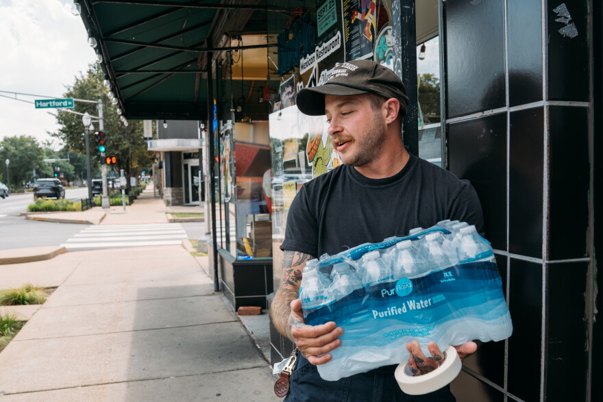 Kenny Marks, owner of Kenny's Upstairs, puts out dozens of bottles of cold bottled water as temperatures climb outside his bar on South Grand Avenue on Sept. 16 in St. Louis' Tower Grove South neighborhood.