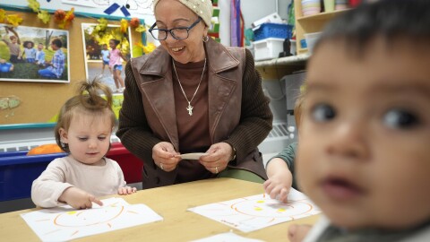 Volunteer Victoria Vasquez, 70, of Providence, R.I., center, supervises one-and-a-half year olds Scarlett Thomas, left, and Liam Echevarria Gaytan, right, in an early childcare program in Providence, R.I.