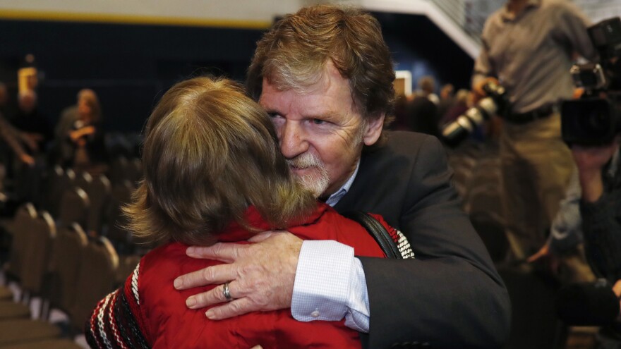 Jack Phillips, owner of Masterpiece Cake, is hugged by a supporter after a rally on the campus of a Christian college in November.