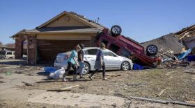 Neighbors walk in front of a home damaged at Wheatland Drive and Conway Drive on Monday, Feb. 27, 2023 in Norman, Okla. The damage came after rare severe storms and tornadoes moved through Oklahoma overnight.