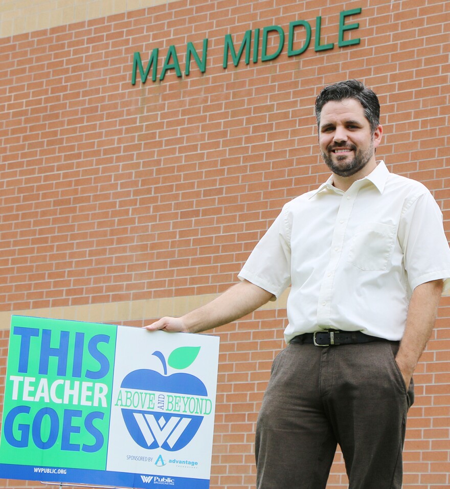 Garron Staten with his Above and Beyond yard sign in front of Man Middle School.
